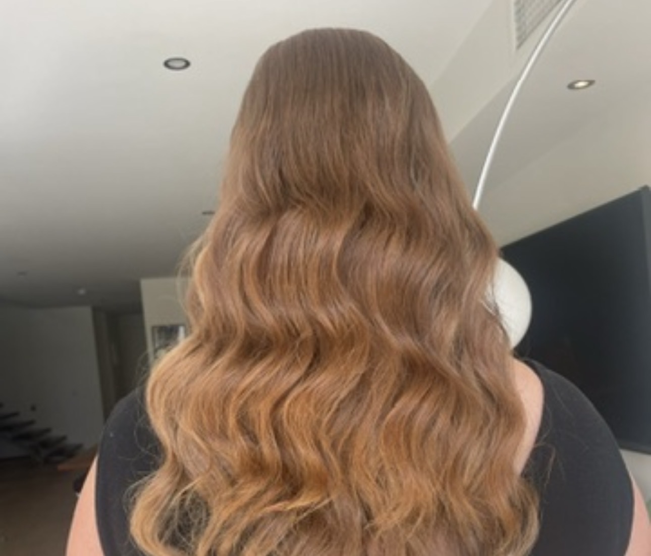Long honey-toned wavy blowout, back view